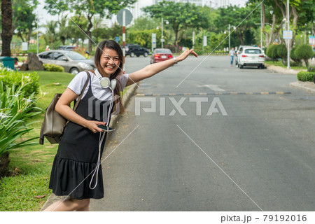 Smiling woman waiting and hailing taxi 79192016