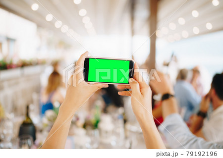 Woman at a wedding banquet filming a party on a smartphone, close-up Woman at a wedding banquet filming a party on a smartphone, close-up 79192196