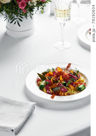 Stewed vegetables with coarsely chopped zucchini, carrots, eggplants and bell peppers, table with white tablecloth, copy space 79192634