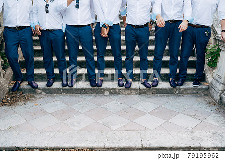 Seven groom's best men in identical blue trousers and shoes stand on the stairs, close-up  79195962