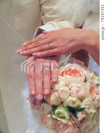 ブーケに添える結婚指輪をした新郎新婦の手 79197391
