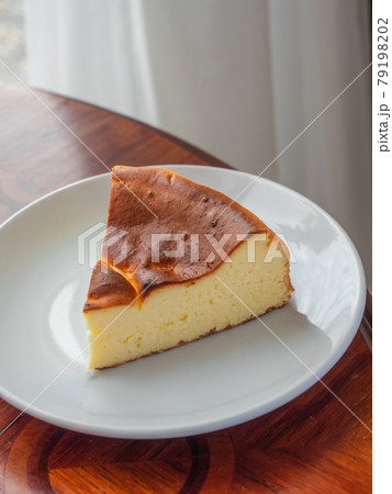 Burnt Basque Cheesecake. A slice of cheese cake with burnt cake surface on white plate. 79198202