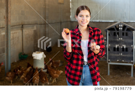 Happy girl standing in hen house with chicken eggs in hands Happy girl standing in hen house with chicken eggs in hands 79198779