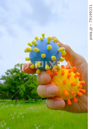 コロナ菌模型を手に持って背景を森林としてアフターコロナをイメージ 79199151