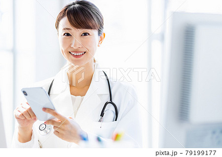 病院内でスマートフォンを見ている女性医師 79199177