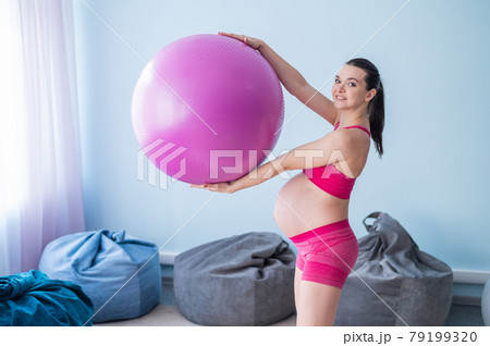 A pregnant woman in sportswear is doing gymnastics for pregnant women. The girl is engaged in fitness with a ball for expectant mothers. Last trimester. A pregnant woman in sportswear is doing gymnastics for pregnant women. The girl is engaged in fitness with a ball for expectant mothers. Last trimester. 79199320