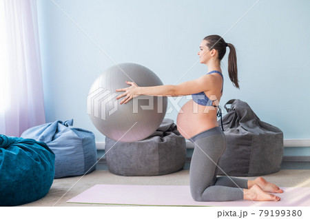 Pregnant caucasian woman on fitness with a ball. Yoga for expectant mothers. Girl in the classroom in preparation for childbirth. Pilates in the last trimester. 79199380