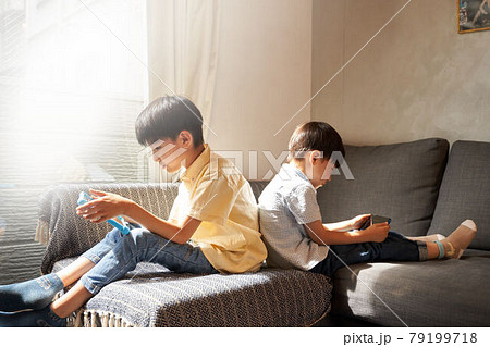 リビングでタブレットの画面を見つめる2人の男の子 79199718