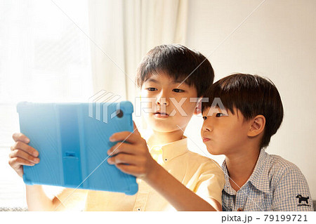 リビングでタブレットの画面を見つめる2人の男の子 79199721
