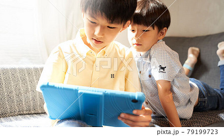 リビングでタブレットの画面を見つめる2人の男の子 リビングでタブレットの画面を見つめる2人の男の子 79199723