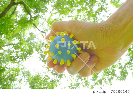 コロナ菌模型を手に持って背景を森林としてアフターコロナをイメージ 79200146