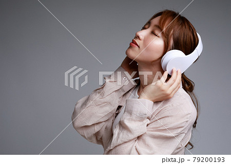ヘッドフォンで音楽に聴き入る若い女性 79200193