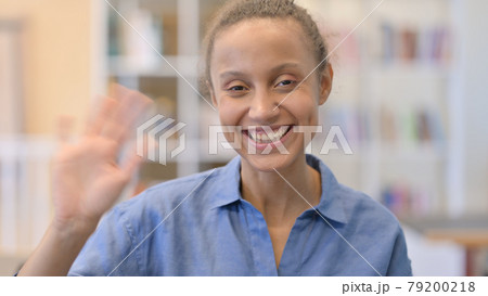 Portrait of Cheerful African Woman Waving at the Camera 79200218