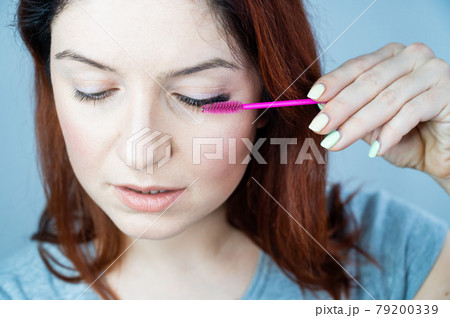 Red head woman brushing her extension eyelashes with a brush. girl with impending eyelid make-up mascara. Beauty industry. Red head woman brushing her extension eyelashes with a brush. girl with impending eyelid make-up mascara. Beauty industry. 79200339