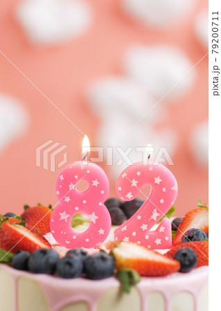 Birthday cake number 82. Beautiful pink candle in cake on pink background with white clouds. Close-up and vertical 79200711