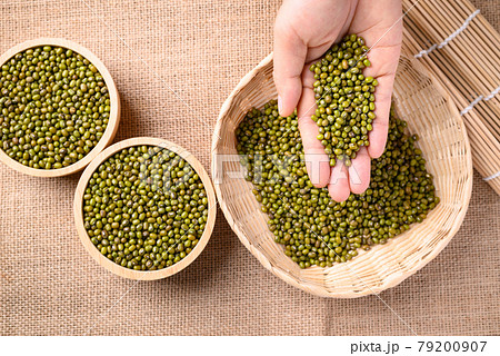 Mung bean seeds in hand and pouring into bamboo basket 79200907