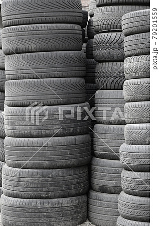 Old used tires stacked with high piles in secondary car parts shop garage 79201559