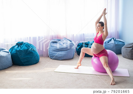 Beautiful pregnant woman doing exercises on a fitness ball. Expectant mother in the last trimester doing yoga. 79201665