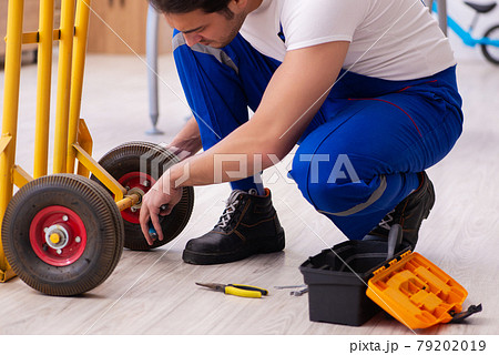 Young male repairman repairing trolley indoors 79202019