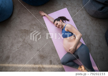 A pregnant European woman is doing pilates alone. Expectant mother in the last trimester practices yoga. The girl is stretched for 9 months. A pregnant European woman is doing pilates alone. Expectant mother in the last trimester practices yoga. The girl is stretched for 9 months. 79202233