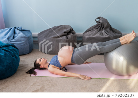 Pregnant european woman performs exercises with fitness ball. Expectant mother is doing yoga in the 3rd trimester. Girl in the classroom in preparation for childbirth. Pregnant european woman performs exercises with fitness ball. Expectant mother is doing yoga in the 3rd trimester. Girl in the classroom in preparation for childbirth. 79202237