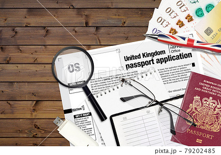 English form OS United Kingdom passport application from HM passport office lies on table with office items. UK passport paperwork English form OS United Kingdom passport application from HM passport office lies on table with office items. UK passport paperwork 79202485