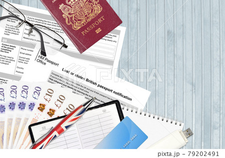 English form LS01 Lost or stolen british passport notification from HM passport office lies on table with office items. UK passport paperwork 79202491