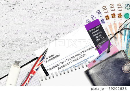 English form BRP RC Application for a replacement biometric residence permit card from UK visas and immigration services lies on table with office items. UK residence permit paperwork 79202628