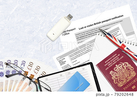 English form LS01 Lost or stolen british passport notification from HM passport office lies on table with office items. UK passport paperwork 79202648
