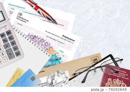 English Tax form sa102 Employment by HM revenue and customs lies on table with office items. HMRC paperwork and tax paying process in United Kingdom 79202649
