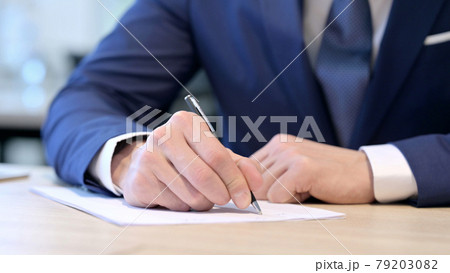 Close up of Hands of Middle Aged Businessman Writing on Paper  79203082