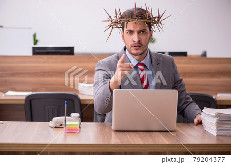 Young male employee wearing prickly wreath on head 79204377