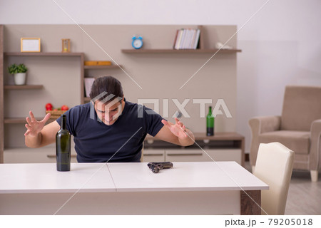 Young male alcoholic committing suicide at home Young male alcoholic committing suicide at home 79205018