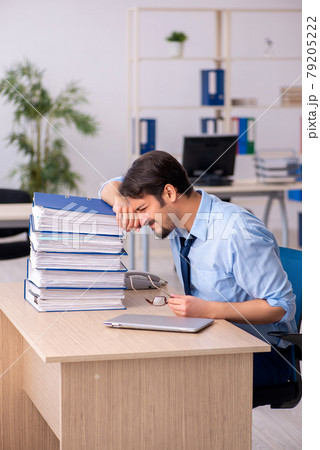 Young male employee and too much work in the office 79205222
