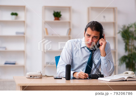 Young male call center operator working at his desk Young male call center operator working at his desk 79206786