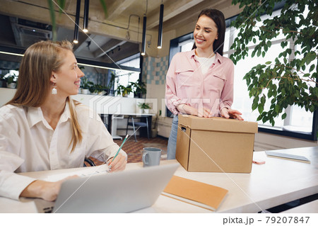 Young businesswoman holding box of personal belongings about to leave office after quitting job Young businesswoman holding box of personal belongings about to leave office after quitting job 79207847