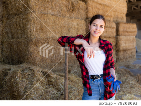 Positive young woman farmer standing with pitchfork in hayloft 79208093