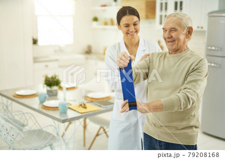 Pensioner and young nurse looking at fitness rubber 79208168
