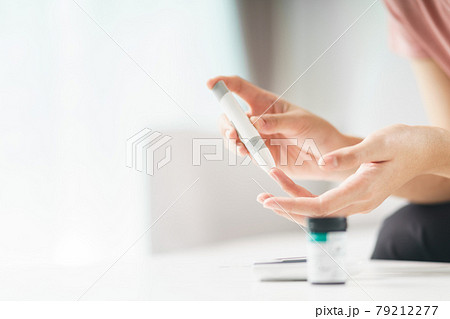 Asian woman using lancet on finger for checking blood sugar level by Glucose meter, Healthcare and Medical, diabetes, glycemia concept. 79212277
