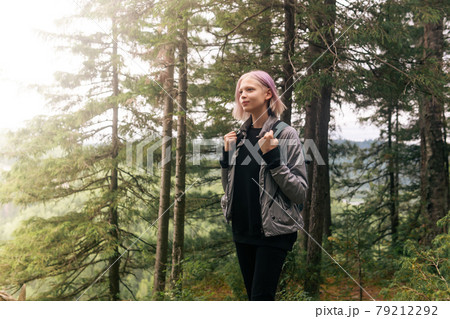 teenage girl with a backpack walks in a mountain forest in the sun 79212292