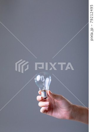 Close up of caucasian businesswoman holding light bulb, isolated on grey background 79212495