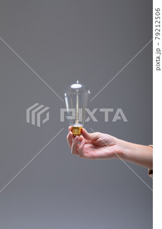 Close up of caucasian businesswoman holding light bulb, isolated on grey background Close up of caucasian businesswoman holding light bulb, isolated on grey background 79212506