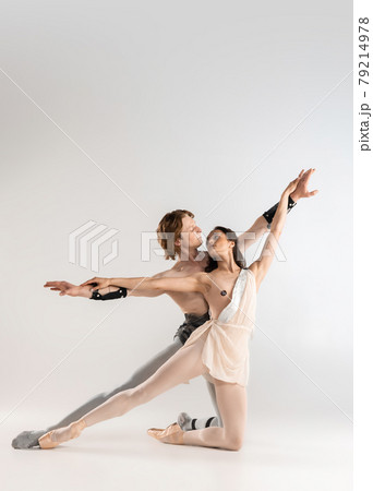 Young couple of ballet dancers in ancient Rome costumes dancing on white studio full of light. Historical character, classical art Young couple of ballet dancers in ancient Rome costumes dancing on white studio full of light. Historical character, classical art 79214978