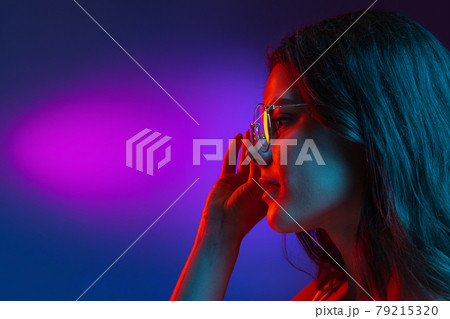 Caucasian young woman's portrait on dark studio background in neon. Concept of human emotions, facial expression. Caucasian young woman's portrait on dark studio background in neon. Concept of human emotions, facial expression. 79215320