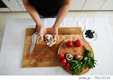 Top view of sliced mushroom in female chef hands. Ingredients for pizza filling on a wooden board in the home kitchen Top view of sliced mushroom in female chef hands. Ingredients for pizza filling on a wooden board in the home kitchen 79215510