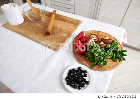 High angle view of ingredients for pizza on wooden kitchen board on a table. 79215513