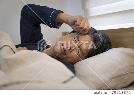 寝ながら汗をかき顔をしかめるミドル男性 79218870
