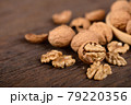 whole and peeled dried walnuts on wooden backbground 79220356