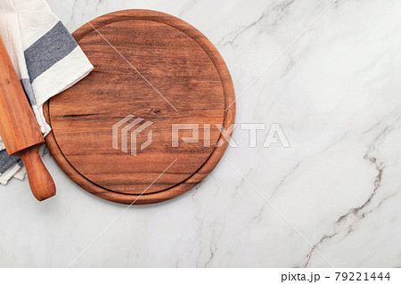 Empty wooden pizza platter with napkin and rolling pin set up on marble stone kitchen table. 79221444
