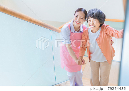 階段を登るシニア女性と介護スタッフ 79224486